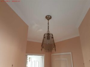 Plafond repeint et lustre reposé après traitement des traces d'humidité